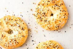 three bagels with sesame seeds and poppy seeds on a baking sheet, ready to be baked