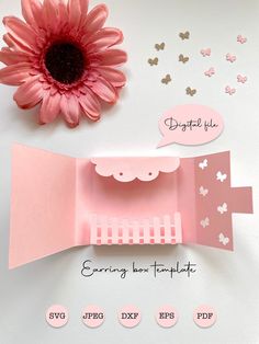 a pink flower sitting on top of a table next to paper cut outs and scissors