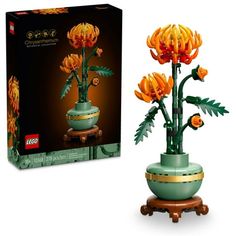 a green vase with orange flowers in it next to a cardboard box that says lego