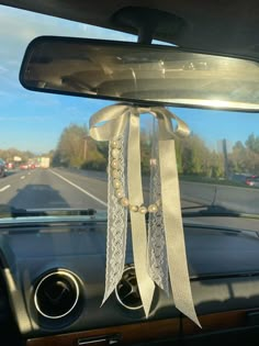 a car dashboard with a white ribbon tied to the dash board and beads hanging from it