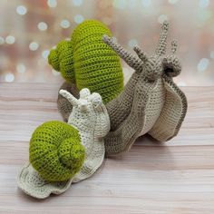 three crocheted stuffed animals sitting next to each other on a wooden table with lights in the background