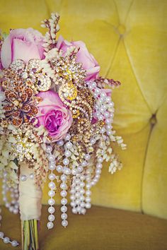 a bridal bouquet with pink roses and pearls on a yellow velvet chair in the background