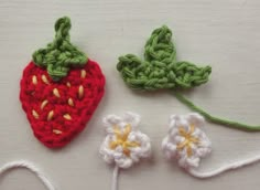 two crocheted strawberries are next to each other on a white surface with yarn