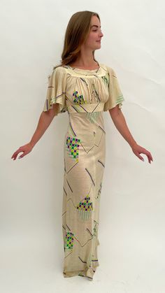 "This 1970s maxi dress is very much influenced by 1930s design and style with its repeating Art Deco geometric design and pretty, fluttery sleeves. The main colour is cream with the highlight colours in shades of green, lilac and purple. The fabric is acrylic which has a slight stretch. It is labelled inside 'Tina Warren Made in England'. There is a zip to the back and a hook and eye fastening.  The inside size label says '36' but this is an old size so please go by all the measurements here to see if it will fit you. When laid flat and fastened the measurements are: Length: 61\" inches Across the waist: 14\" inches Across the hips: 17\" inches From underarm to underarm across: 16\" inches Across the band under the bust: 13.5\" inches  It is in good overall condition with the following age Vintage Beige Short Sleeve Maxi Dress, Beige Short Sleeve Vintage Maxi Dress, Beige Vintage Short Sleeve Maxi Dress, Beige Vintage Maxi Dress With Short Sleeves, 1930s Design, 1970s Dress, 1970s Style, Art Deco Geometric, 1970s Dresses