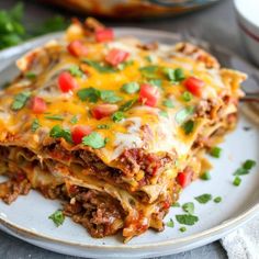 a white plate topped with lasagna covered in meat and cheese, garnished with cilantro