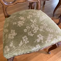 an upholstered chair sits on the floor in front of a wooden table and chairs