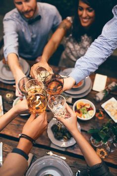 group of people toasting with wine glasses at dinner table