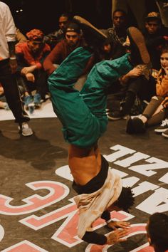 a man doing a handstand in front of a group of people on the floor