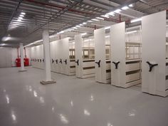 a row of white stalls with black handles in an empty warehouse area, all lined up against the wall