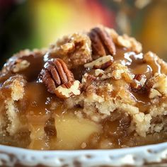 a close up of a piece of cake on a plate with pecans in the background