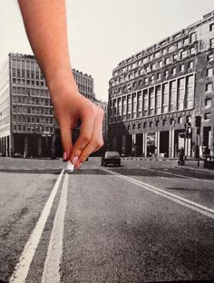 a person's hand reaching for something in the middle of an empty city street