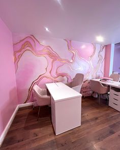 an office with pink walls and white desks in front of a large painting on the wall