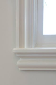 the corner of a white wall with a window in it