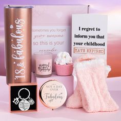 the contents of a pink gift set including a cupcake, candle and other items