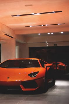 an orange sports car is parked in a showroom with other cars behind the vehicle