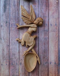 a wooden spoon with a carved cup on top of it next to a wall clock