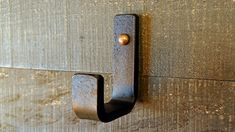 a door handle on the side of a wooden wall with a metal hook attached to it