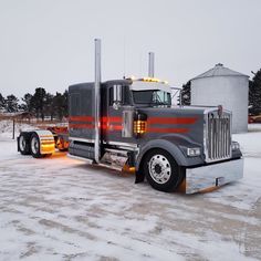 a large semi truck parked on top of a snow covered field