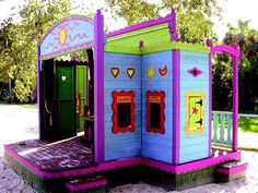 an outdoor play structure with colorful paint on the walls and doors, painted in bright colors