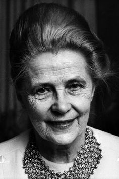 an older woman wearing a necklace and smiling at the camera, black and white photograph