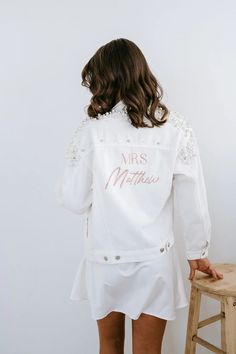 a woman standing next to a stool wearing a white jacket with the words mrs matter written on it