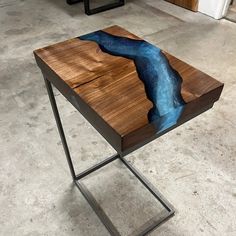 a wooden table with a river painted on the side and metal legs in front of it