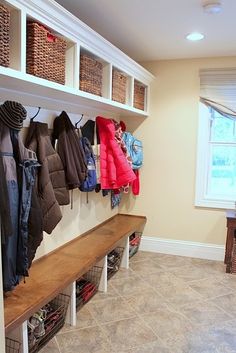 a coat rack filled with coats next to a bench in a room full of shoes