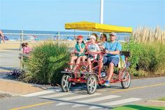 three people are riding in a cart on the road by the beach with an umbrella over them