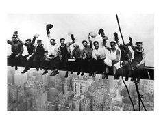 a group of men sitting on top of a tall building with their feet in the air