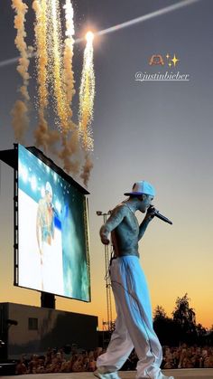 a man is walking in front of a large screen with fireworks coming out of it