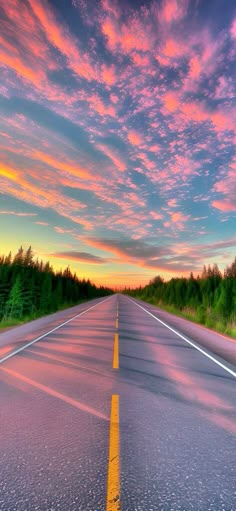 an empty road with the sun setting in the background and trees on both sides,