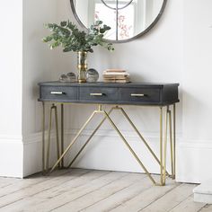 a black and gold console table with a plant on it in front of a round mirror