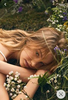 a woman laying in the grass with flowers around her