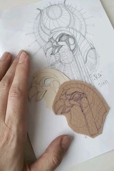 a hand holding a piece of paper next to some drawings