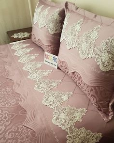 a bed with pink sheets and pillows on it