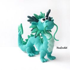 two crocheted dragon figurines sitting next to each other on a white surface