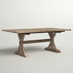 a wooden table sitting on top of a white floor next to a gray wall in an empty room