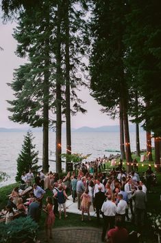 a group of people standing on top of a lush green hillside next to the ocean