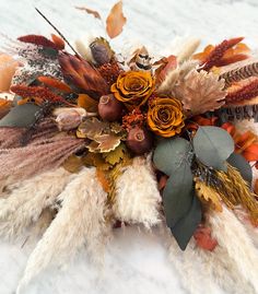 an arrangement of dried flowers and feathers in the snow