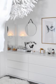 a white bathroom with two mirrors above the sink and other items on the counter top