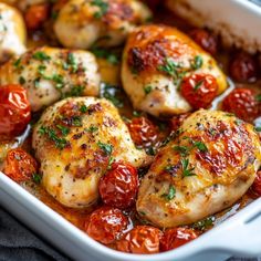 chicken with tomatoes and herbs in a white casserole dish