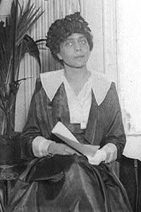 an old black and white photo of a woman sitting on a chair with a book in her lap