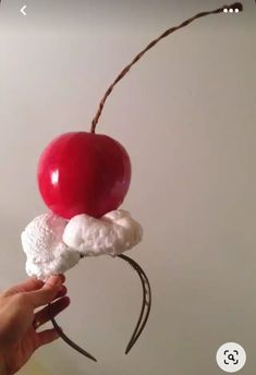 a person holding an object made out of marshmallows, cherries and whipped cream