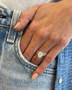 a close up of a person's hand with a ring on their finger, wearing jeans