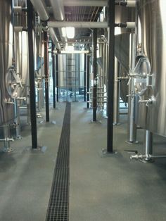 the inside of a winery with stainless steel tanks lined up against the wall and floor