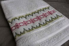 a close up of a white towel with red and green trimmings on it