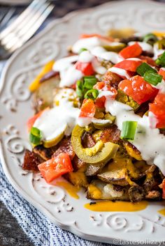 a white plate topped with an enchilada covered in sour cream and toppings