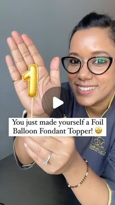 a woman wearing glasses holding up a piece of cake on a stick that says you just made yourself a foil balloon fondant topper