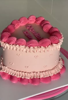 a cake with pink icing and hearts on it sitting on top of a table