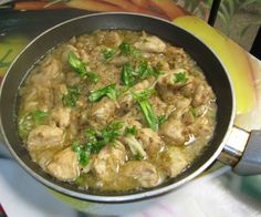 a pan filled with chicken and broccoli on top of a stove burner